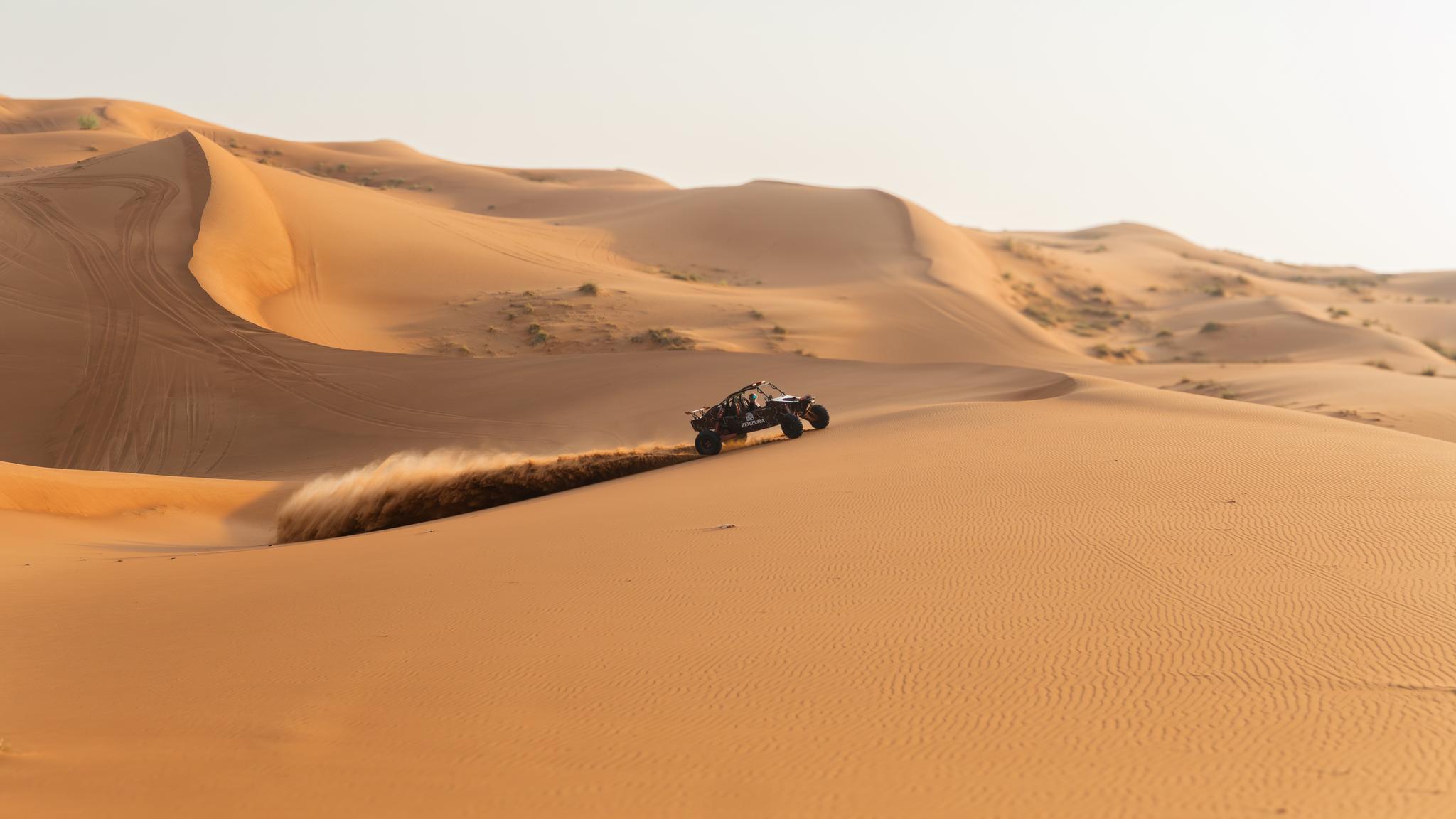 Dune buggy climbing sand dune in Mleiha desert during Zerzura buggy experience