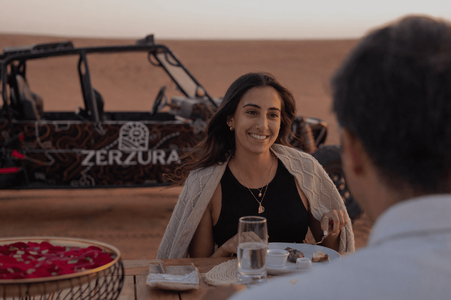 Couple enjoying private desert dining near Zerzura dune buggy in Mleiha