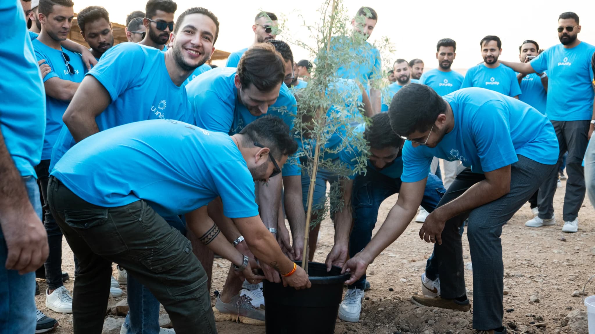 Team members planting a tree together during a CSR activity
