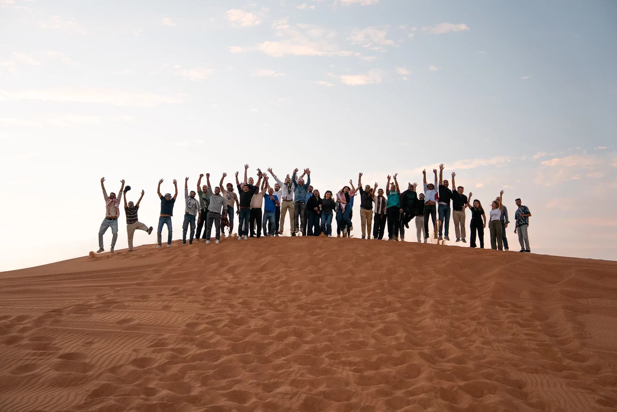 A group celebrating together on a desert dune