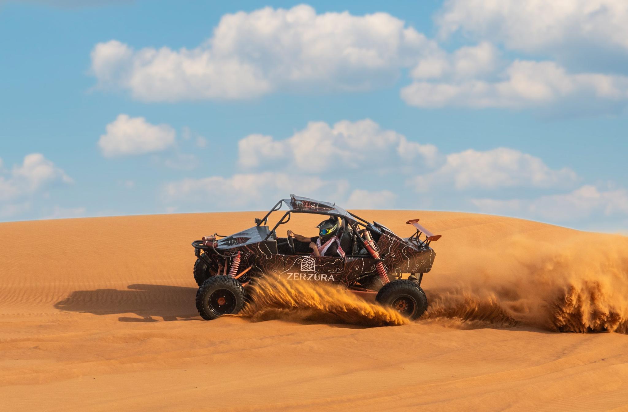 Guests driving a dune buggy through the golden dunes of Mleiha near Dubai
