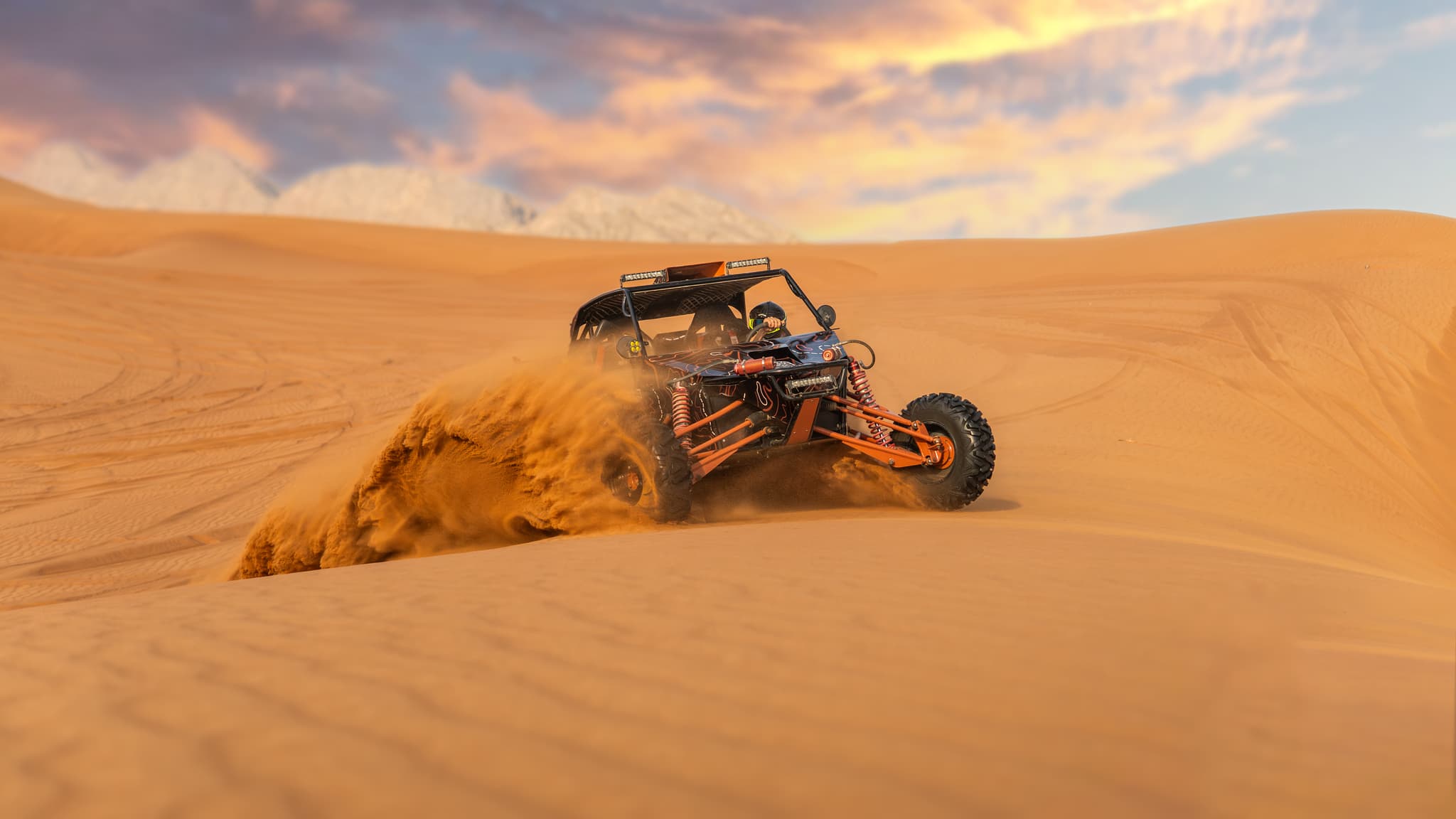 Person riding a high-performance dune buggy across golden desert dunes at sunset during Zerzura’s Desert Safari Dubai adventure.