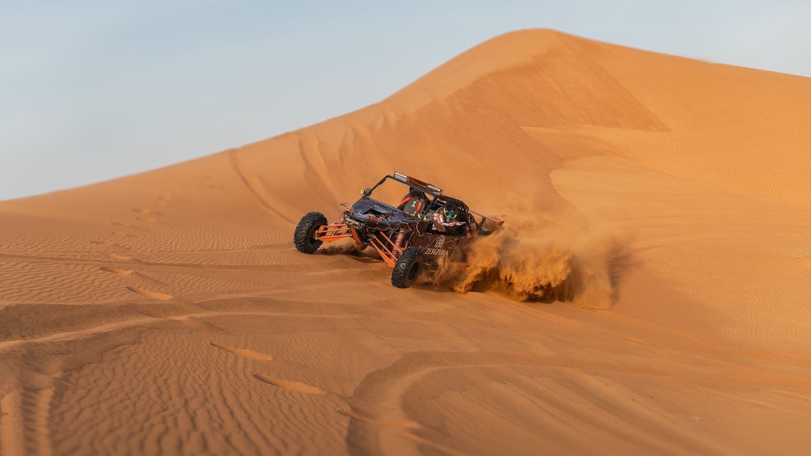 A Zerzura dune buggy carving across a sand dune near Mleiha
