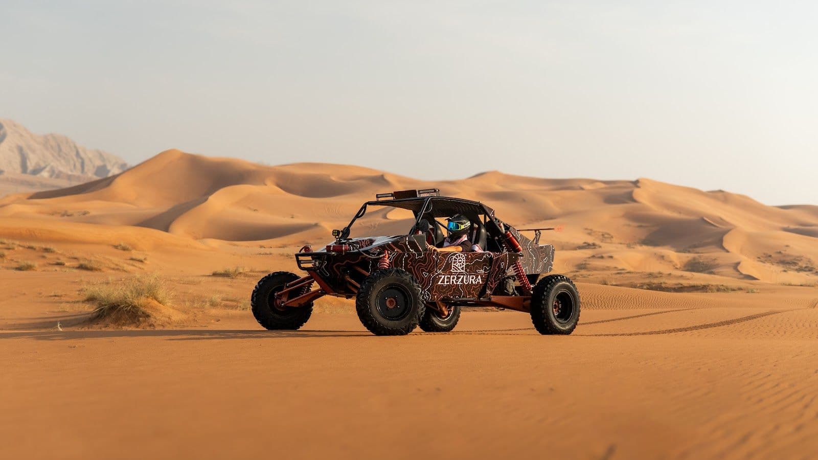 Zerzura dune buggy with a helmeted driver in the Mleiha desert